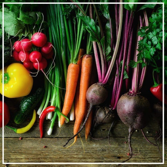 Raw-ingredients-banner Collection of mixed vegies freshly harvested from the garden laying on a wooden benchtop