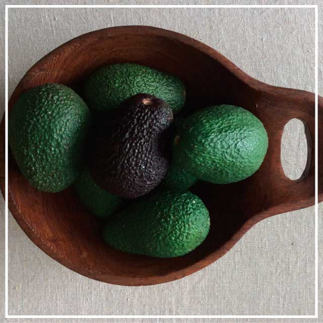 Fresh Avocardos Birds eye view of wooden bowl of fresh avocardos sitting on top of a beige benchtop